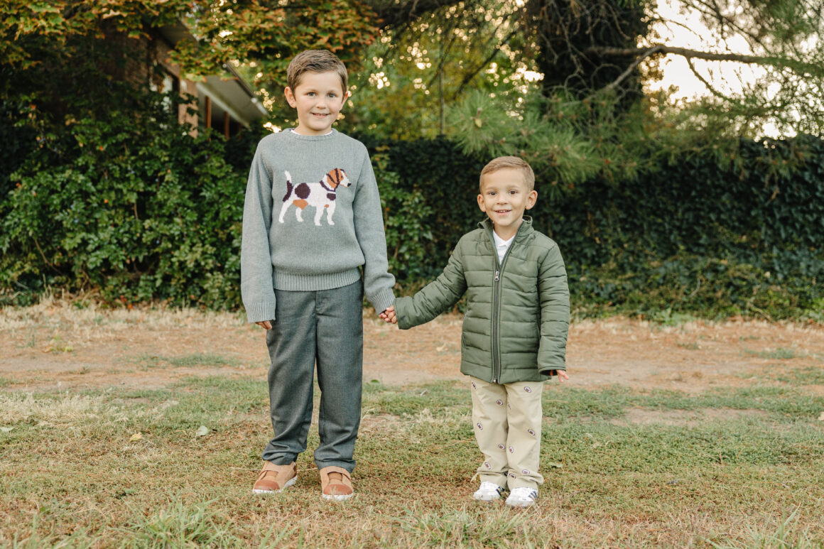 Older boy wearing a warm sweater and pants, toddler wearing a quilted puffy jacket and pants from Pedal Kidswear winter collection.