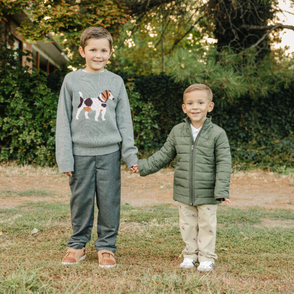 Older boy wearing a warm sweater and pants, toddler wearing a quilted puffy jacket and pants from Pedal Kidswear winter collection.