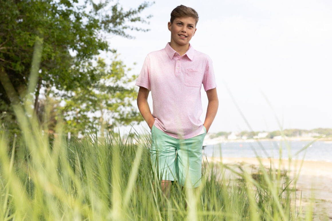 Boy wearing a polo shirt and a tee in a field, showcasing a casual spring look for boys from the new Spring collection.