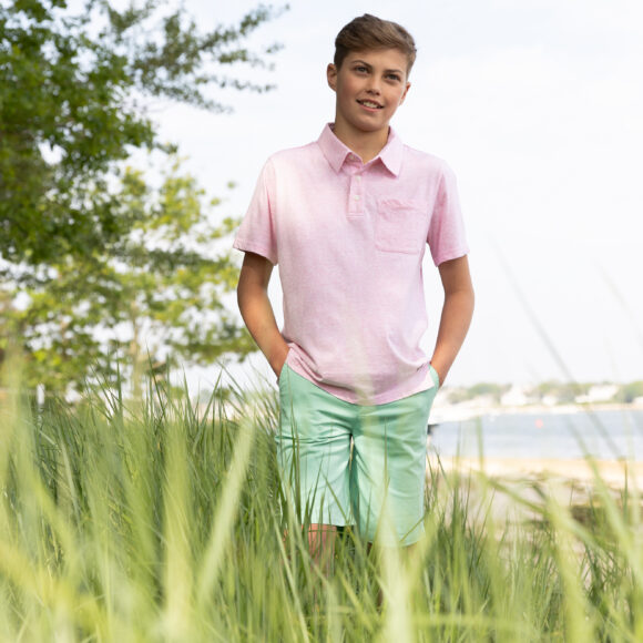 Boy wearing a polo shirt and a tee in a field, showcasing a casual spring look for boys from the new Spring collection.