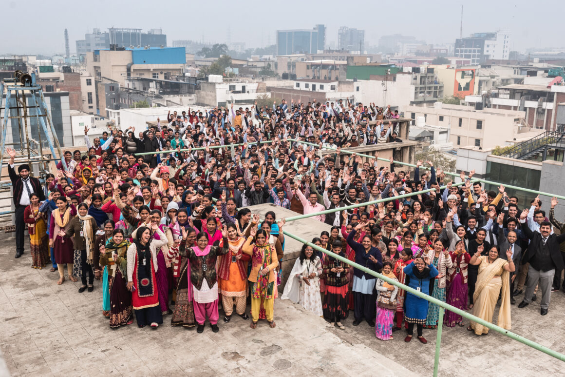 Pedal Kidswear factory team in India smiling and waving — sustainable kids clothing made by real people