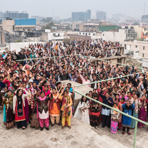 Pedal Kidswear factory team in India smiling and waving — sustainable kids clothing made by real people