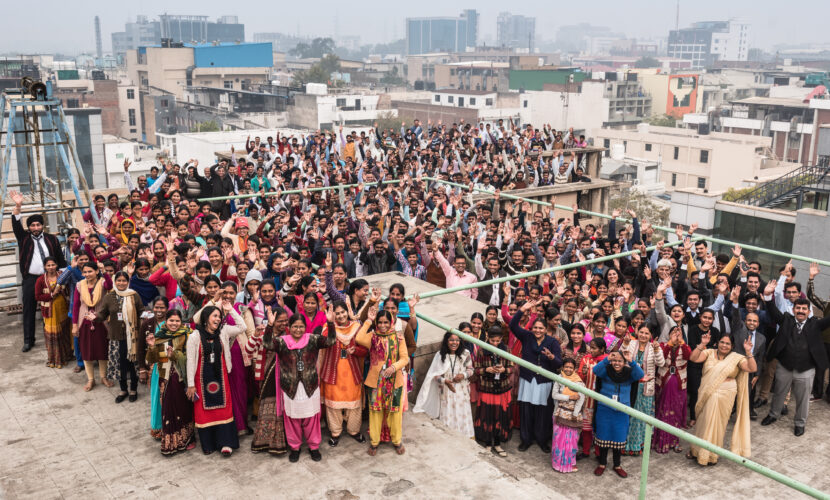 Pedal Kidswear factory team in India smiling and waving — sustainable kids clothing made by real people